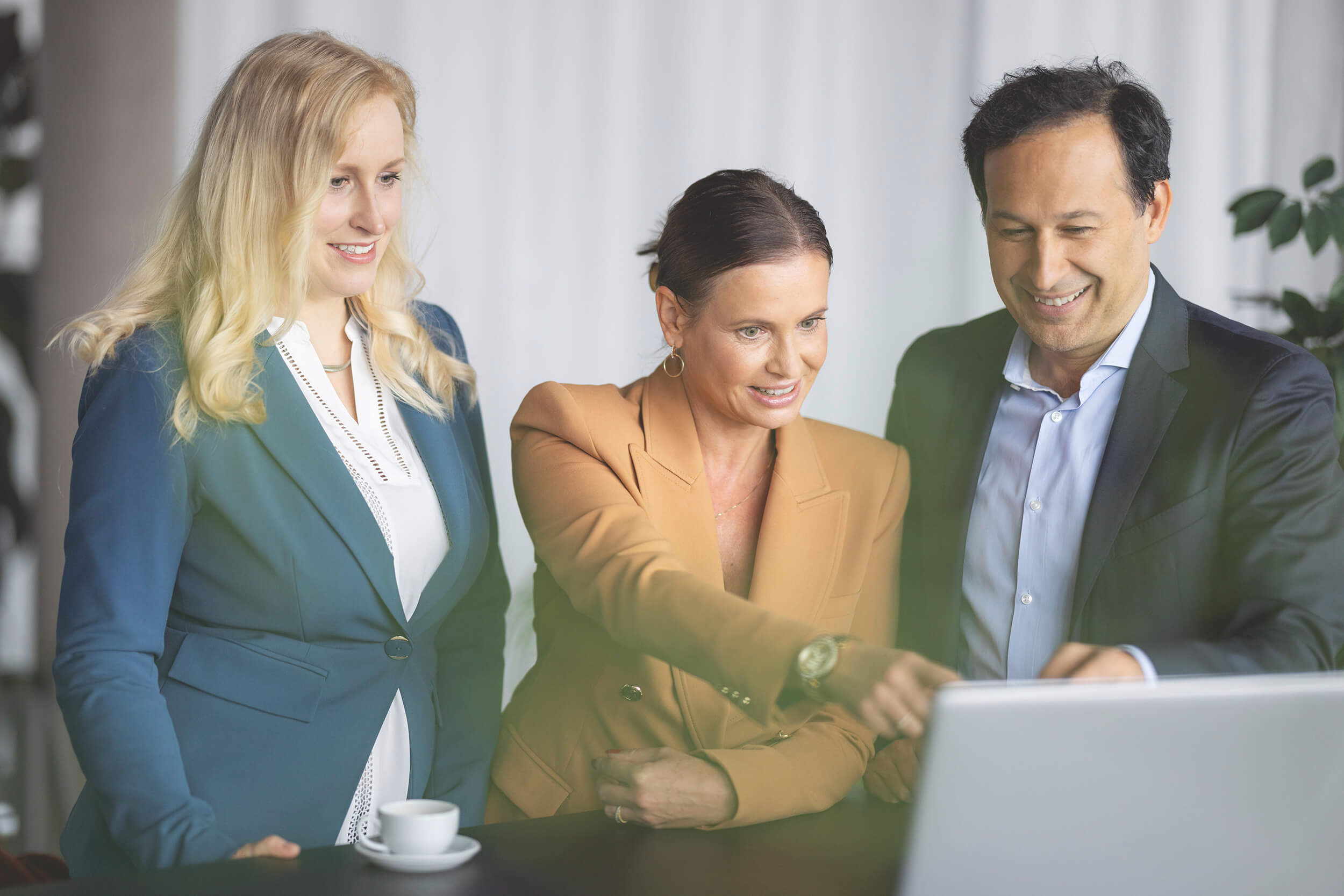 Office managerin Ina Steffens zeigt 2 Mitarbeitern etwas auf dem Computer