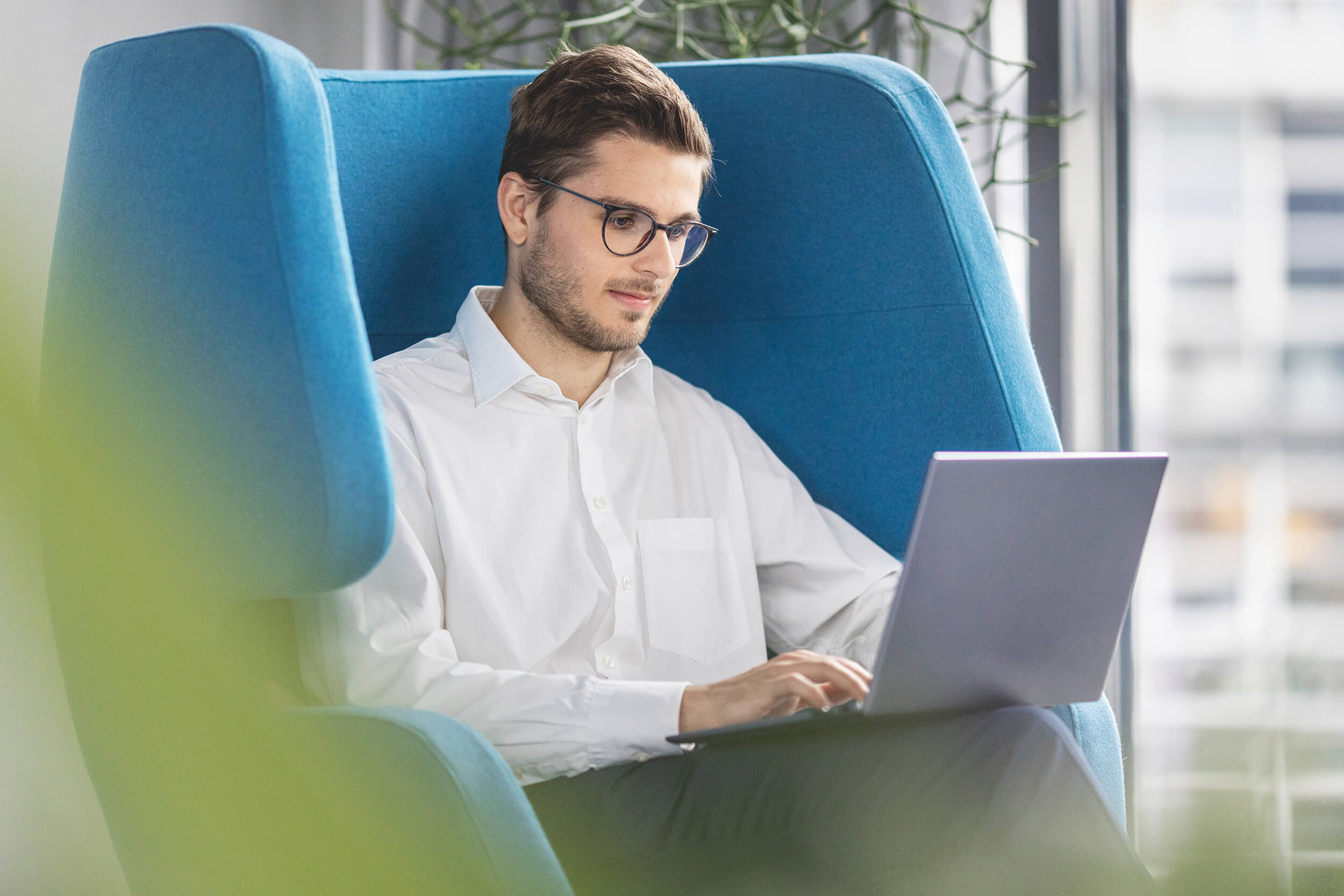 Mitarbeiter im blauen Ohrensessel im Homeoffice