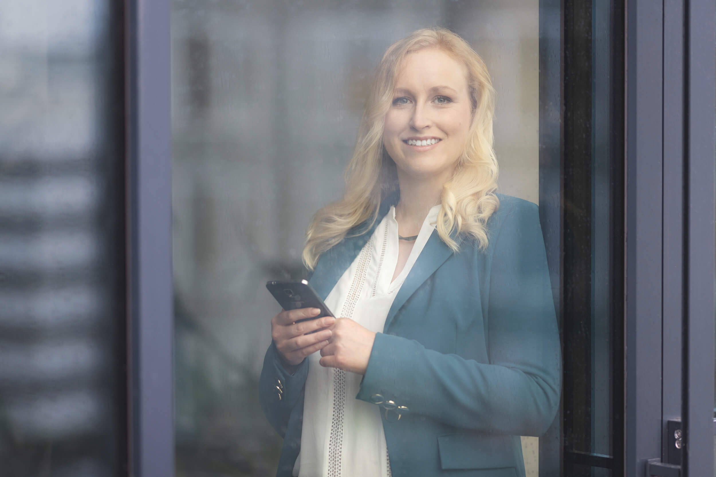 Steuerberaterin Sina Steinecke am telefon hinter einem Fenster