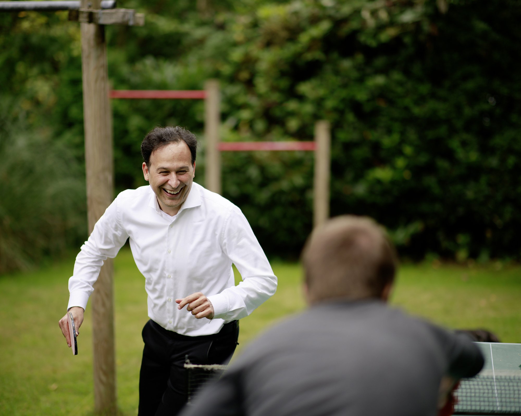 Geschäftsführer Durica Radenovic lachend beim herum laufen um die Tischtennisplatte