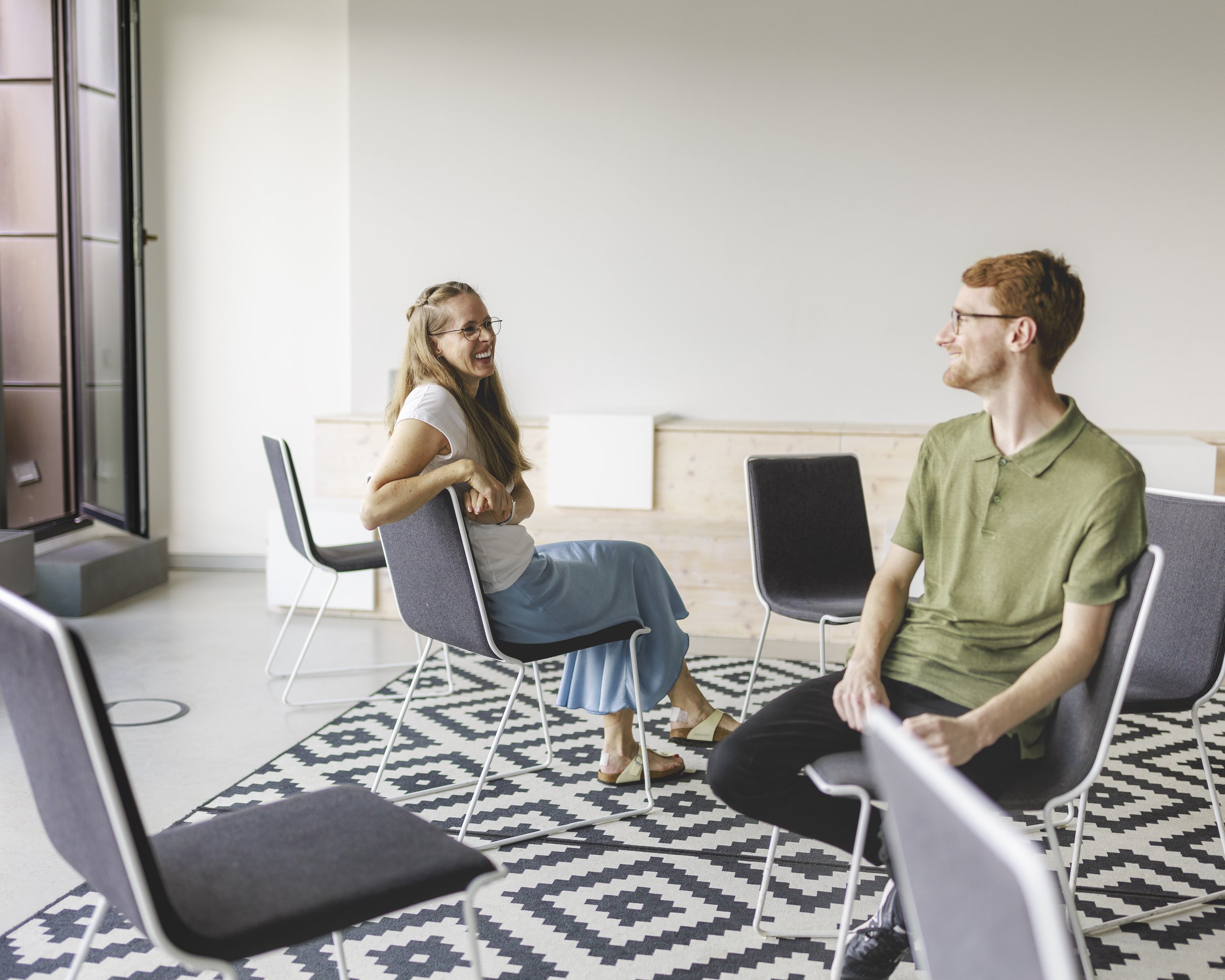 Severine Lanser und Jan Maximilian Lemmermann von ETL HERATAX haben Spaß, sitzen sich schräg gegenüber mit versetzten Stühlen.